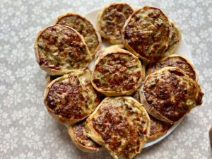 Freshly baked Udmurt perepechi—open-faced rye tartlets filled with ground pork and mushrooms, resting on a parchment-lined tray.